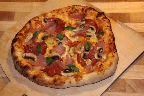 Pizza Speciale mit Schinken, Salami und Pilzen frisch aus dem Ofen